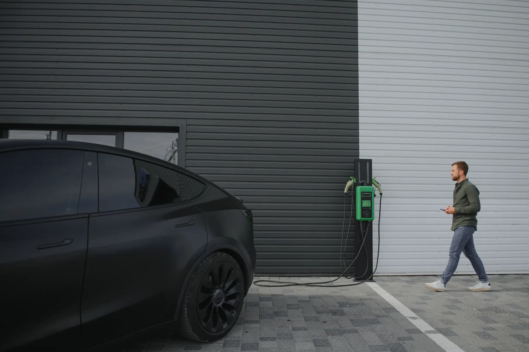 Man walking with phone to parked Tesla Model X