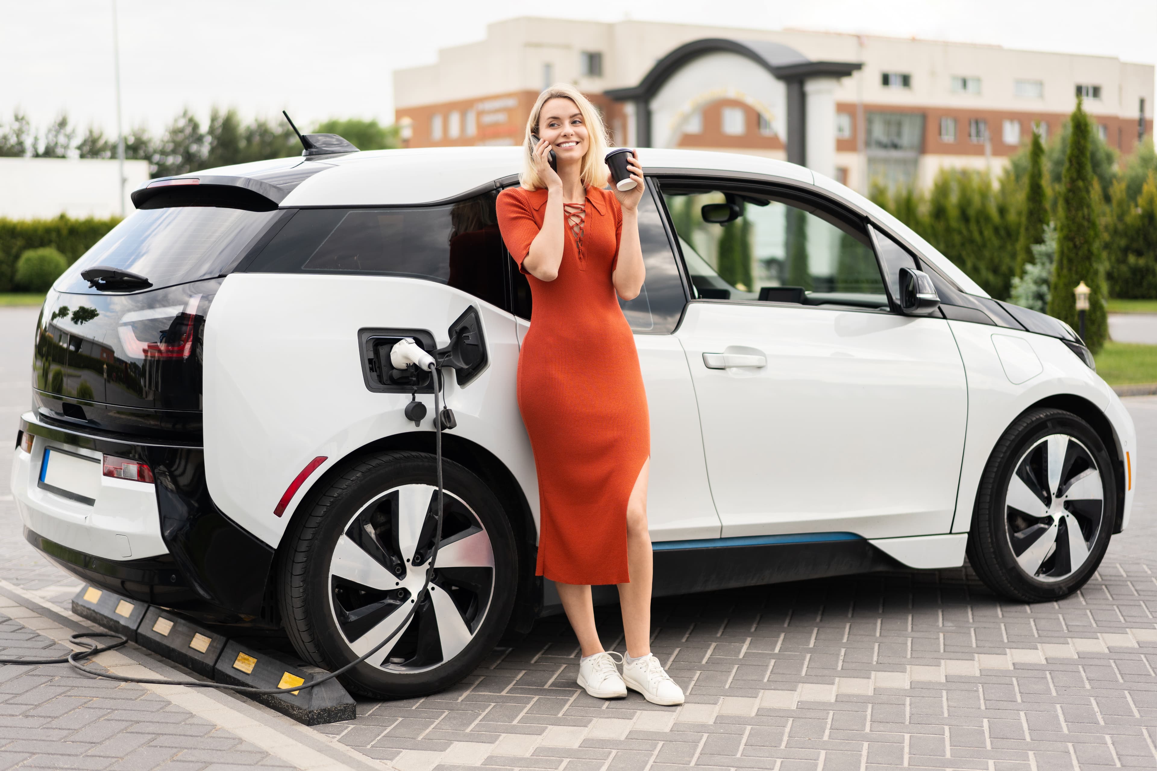 Woman holding phone and charging car