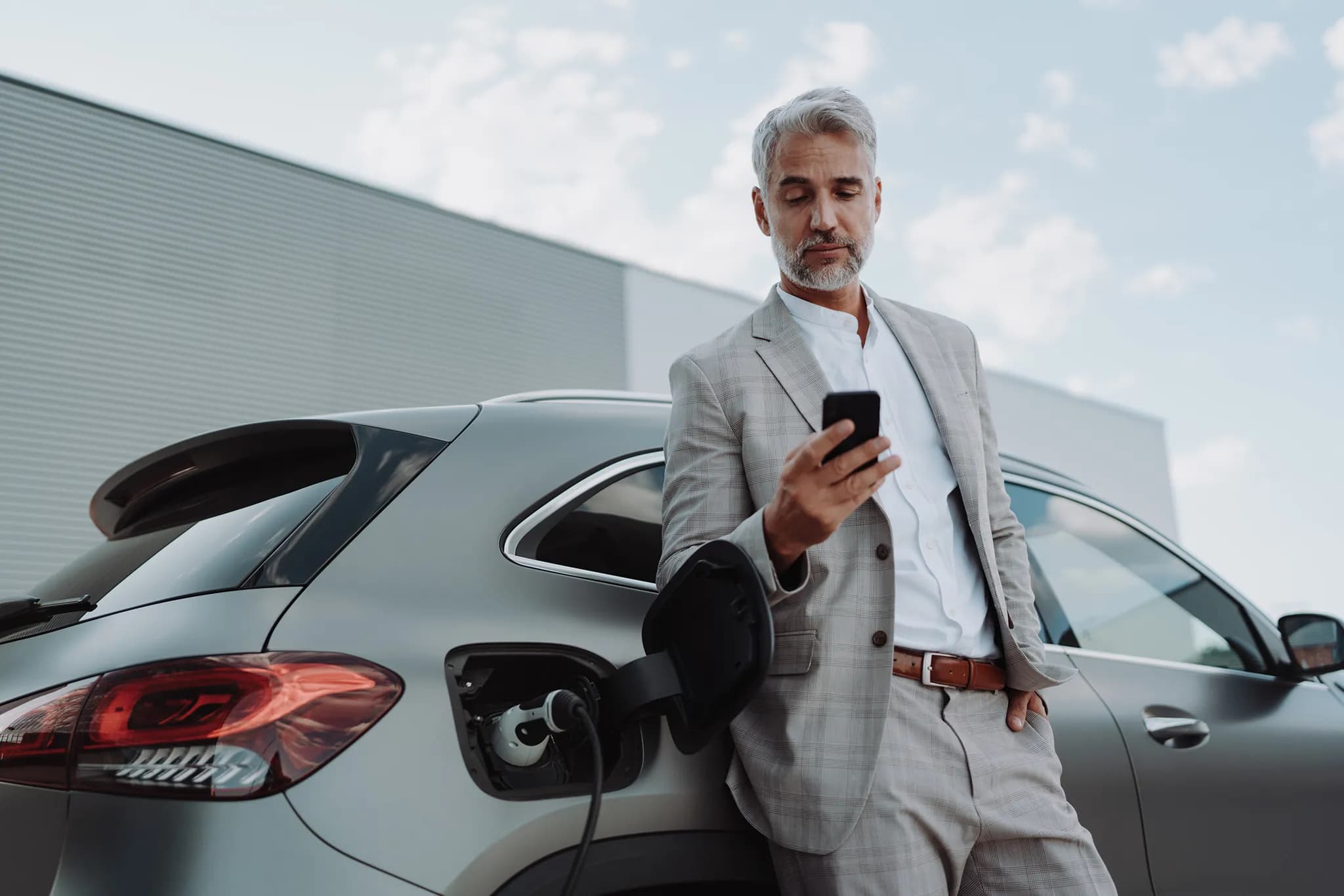 Woman holding phone and charging car