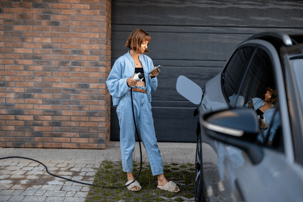 Woman holding phone and charging car