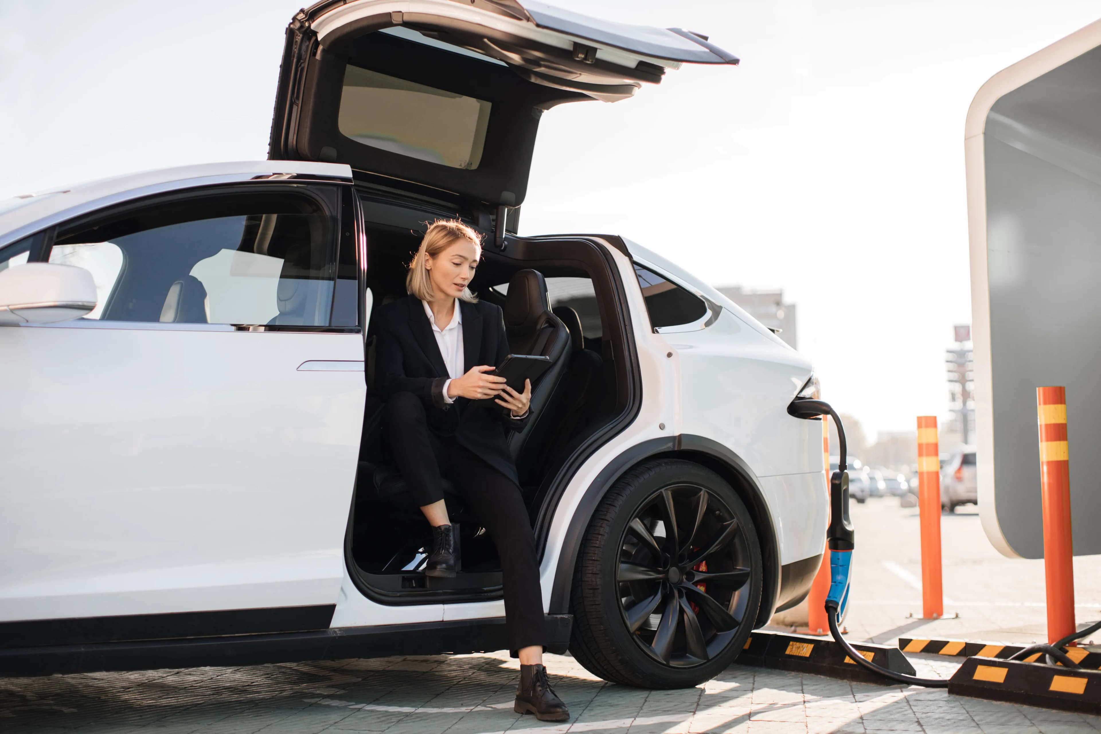 Woman holding phone and charging car